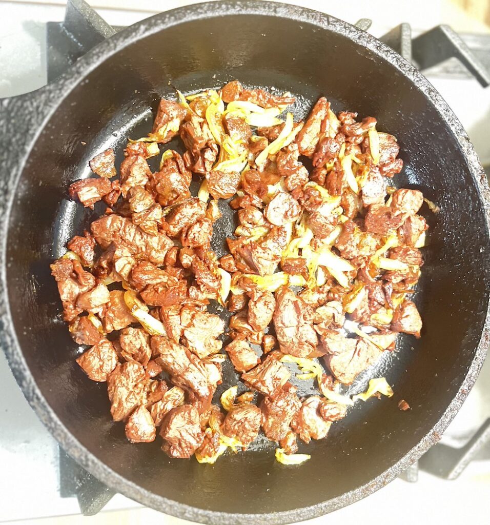 frying Beyond Meat steak pieces with onions
